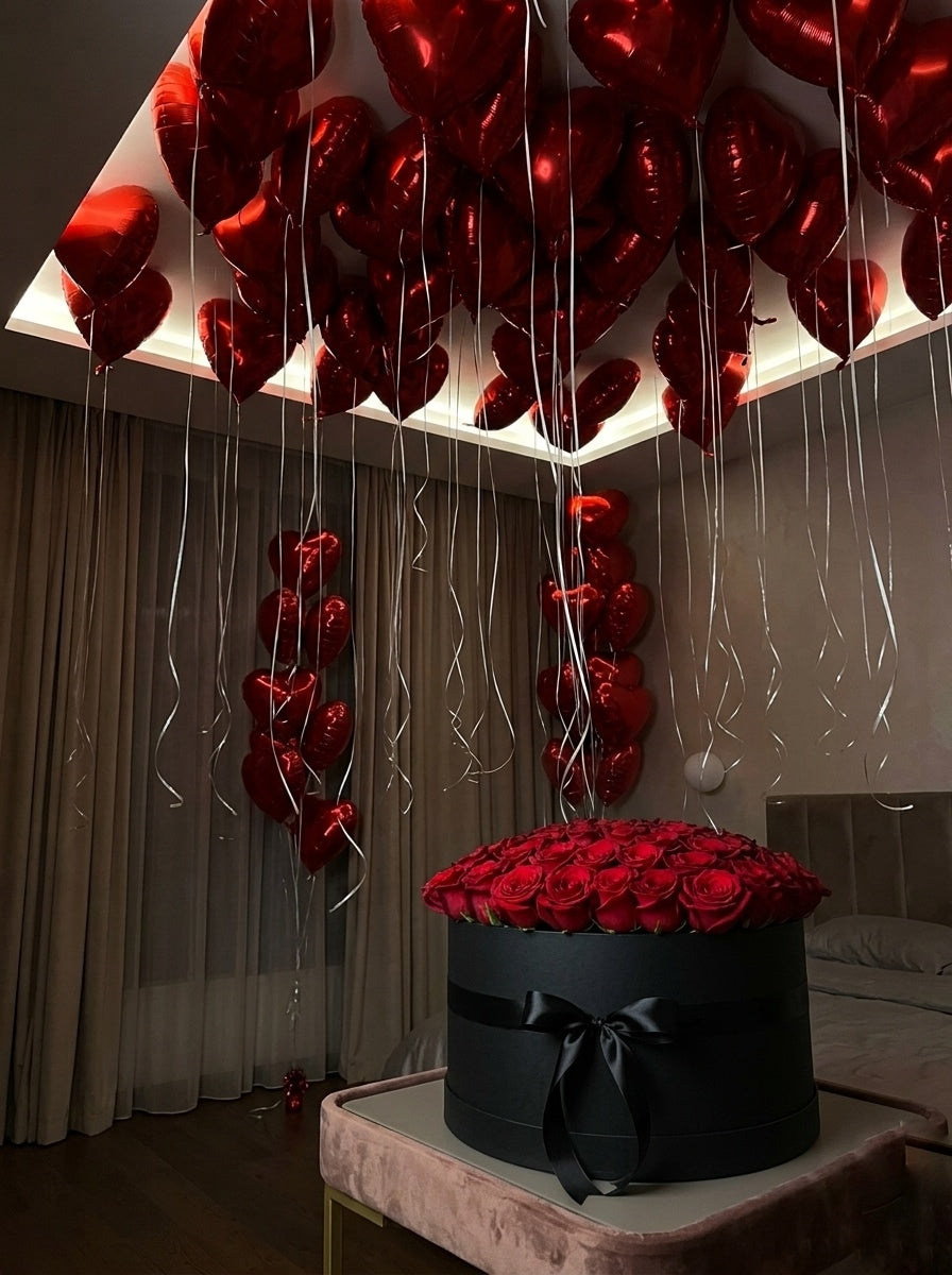 A large  box filled with red roses, with many red heart-shaped balloons